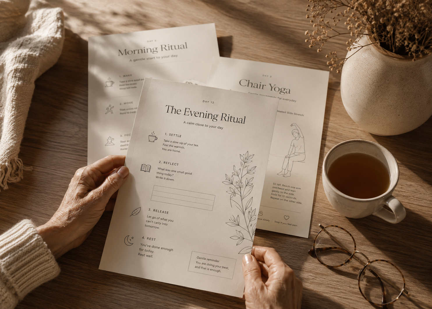 Hands holding a printed Evening Ritual page beside a cup of tea on a wooden table